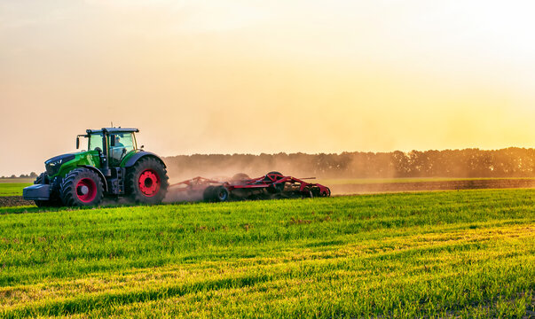 Fototapeta a tractor in a field under the sunlight of dawn plows a field. High quality photo
