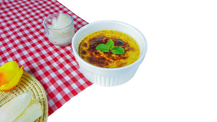 Creme Brulee in a white cup on red check tabke cloth.