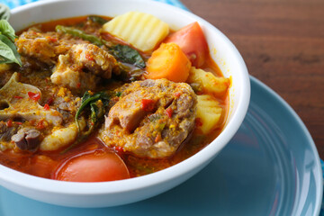 Close up photo of a portion of Indonesian special oxtail soup, served in a bowl and a blue tablecloth