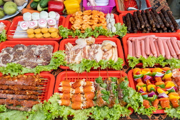 Obraz na płótnie Canvas Raw steaks, sausages, meat, and vegetables on skewers in Vietnamese street market
