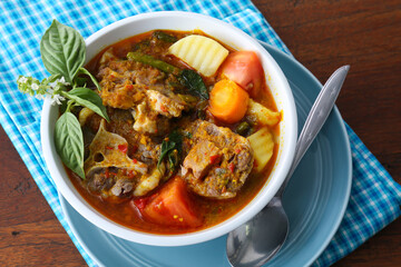 Close up photo of a portion of Indonesian special oxtail soup, served in a bowl and a blue tablecloth