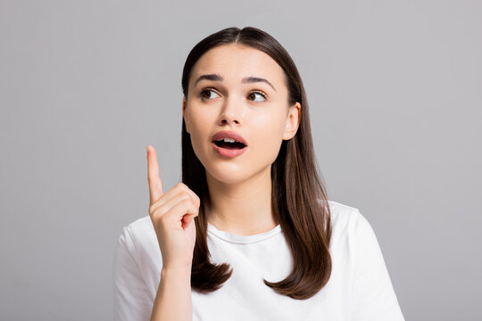 Close up shot selective focus on surprised screming woman in white shirt standing on white background looking into distance.