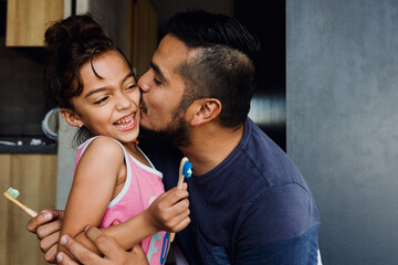latin young father teaching to his daughter how to brush teeth at home in Mexico Latin America	