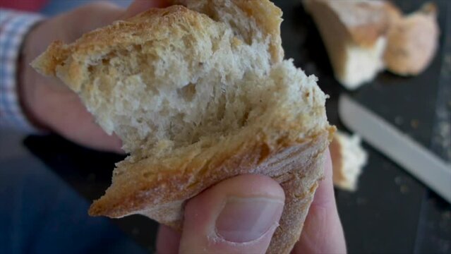 static macro slow motion shot of man's fingers breaking the white bread