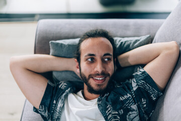 high angle view portrait photo of young satisfied man lying on sofa at home