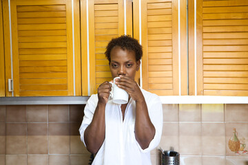 Young and beautiful Afro American woman has a cup of coffee when she just woke up. Breakfast of...