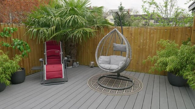 Minimalistic UK summer garden showing swing chair decking and sun lounger.