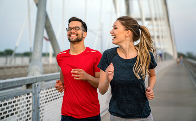 Fototapeta na wymiar Early morning workout. Happy couple running across the bridge. Living healthy lifestyle.