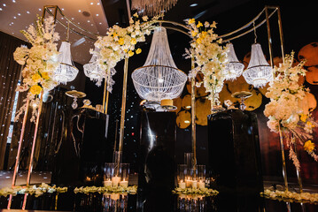 Delicious luxury wedding reception. Birthday Cake on party. Celebration concept. Candy bar. Table with sweets, candies, dessert. Arch with large chandelier, flowers, candles, rose petals on floor hall