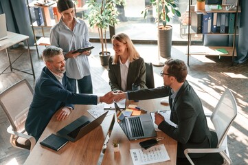 Successful deal, doing handshake. Group of business people are working in the modern office