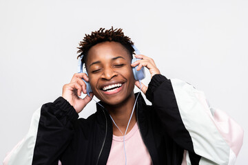 Happy relieved dark skinned guy hipster wearing stylish new clothes and plaing pink t-shirt closing eyes listening to music enjoying favorite songs during shooting process. - obrazy, fototapety, plakaty