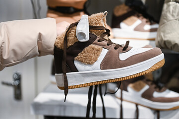 Brown sneakers with laces in the hands of the buyer. shoplift protection, warm shoes