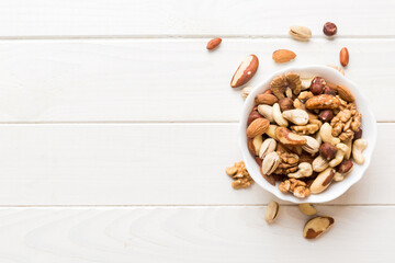 mixed nuts in bowl. Mix of various nuts on colored background. pistachios, cashews, walnuts, hazelnuts, peanuts and brazil nuts - obrazy, fototapety, plakaty