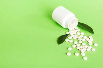 Medicine bottle and white pills spilled on a light background. Medicines and prescription pills flat lay background. White medical pills and tablets spilling out of a drug bottle