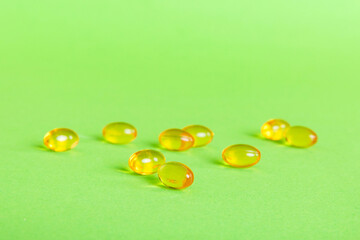 Heap of yellov pills on colored background. Tablets scattered on a table. Pile of red soft gelatin capsule. Vitamins and dietary supplements concept