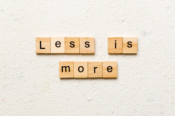 less is more word written on wood block. less is more text on table, concept