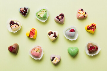 chocolate sweets in the form of a heart with fruits and nuts on a colored background. top view with space for text, holiday concept