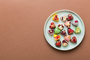 Plate with different chocolate on colored background. Assortment of fine chocolates top view vith copy space Health and obesity concept
