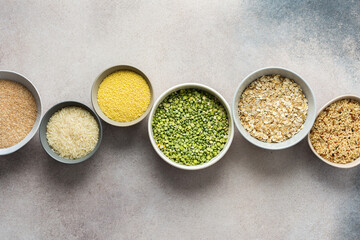 Various grain cereals in bowls on a light background, top view
