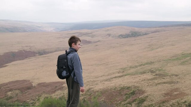 Young boy outdoors standing on a countryside hill top, admiring the moorland views. UK