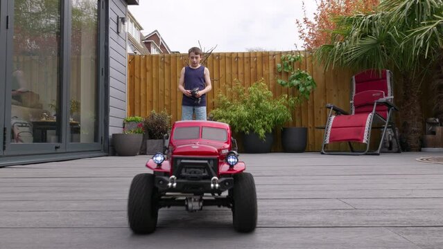 Young boy at home outdoors in the garden playing with his RC Car, Truck, 4 x 4