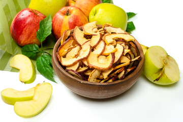 Dry apple slices in a bowl and fresh apples on white background. Dehydrated snacks of apple fruits....
