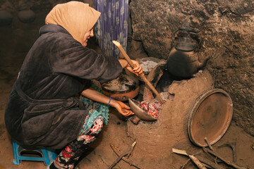 Berber woman in old traditional kitchen preparing wood oven for cooking