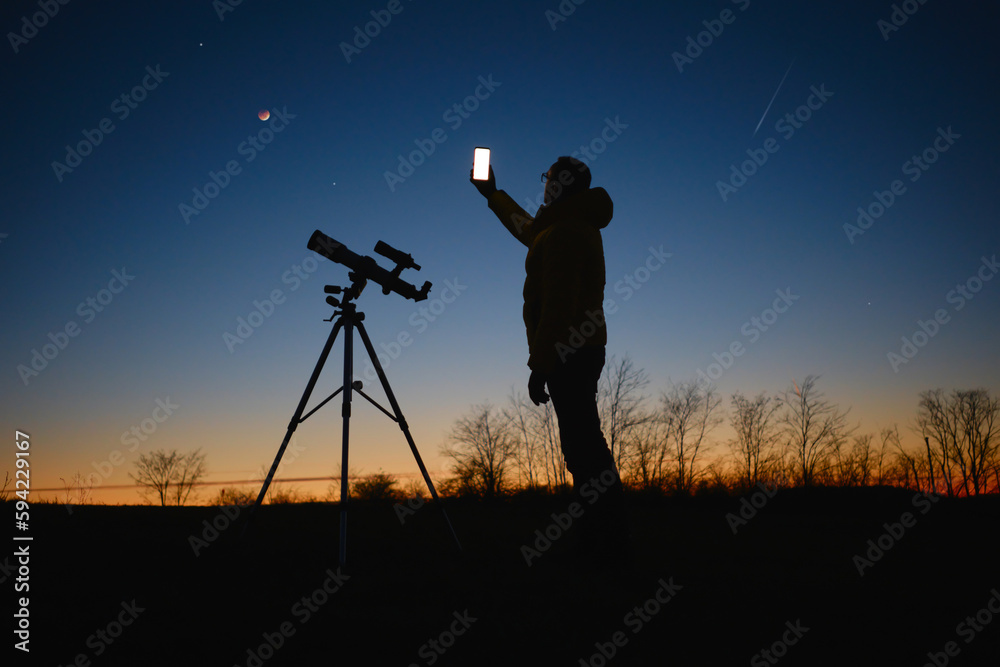 Canvas Prints astronomer looking at the starry skies with planets, falling stars and moon eclipse with a telescope