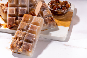 Tapioka latte popsicles. Frozen tapioca boba balls coffee frappe, ice cream lollypops made with asian cold tapioca coffee, with coconut cream and caramel sauce