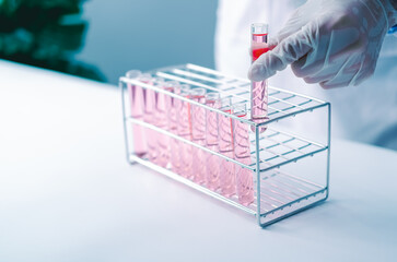 Scientist hand holds test tubes filled with red chemicals sample for experimental in chemistry...
