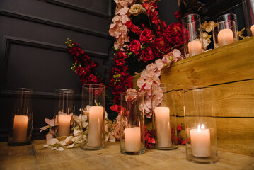 Decor with candles for surprise marriage proposal. Romantic date in restaurant. Candlelight setup decor for couple on Valentine's day. Location with arch, wall, photo zone decoration flowers. Wedding.