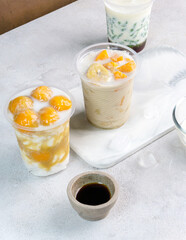 Kolak pisang ubi, kolak biji salak is Indonesian Dessert during Ramadhan made from banana, sweet potato cooked with coconut Milk, palm Sugar. Serving in plastic glass, white background.