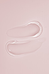 Squeezed cosmetic clear cream gel texture Iisolated on beige background. Close up transparent serum drop smears