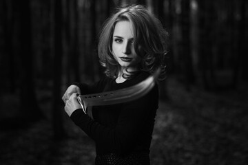 Attractive woman in black holding a sword in a forest