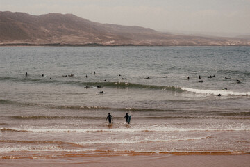Fototapeta na wymiar Surfers walking into sea Stock Photos and Images -Surfing Imsouane Morocco
