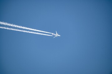 Jet plane flying overhead diagonally with condensation trail.