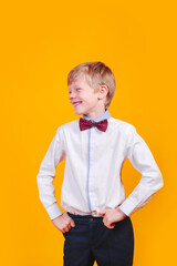Kid boy looking to the side in bowtie on yellow background.