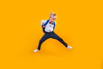 Fototapeta na wymiar Little school boy student jumpsing high like a super hero on yellow background