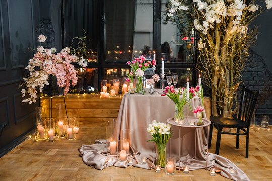 Romantic date. Table setting in restaurant. Luxury candlelight dinner setup table for couple on Valentine's day. Location decoration tulips flowers, decor candles for surprise marriage proposal.