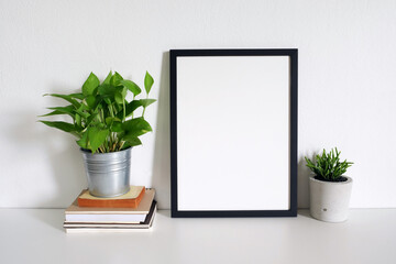 blank frame picture with plants on table in room