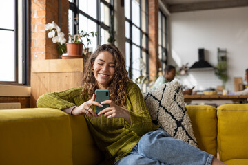 Female Student on Sofa using a Smartphone in loft apartment