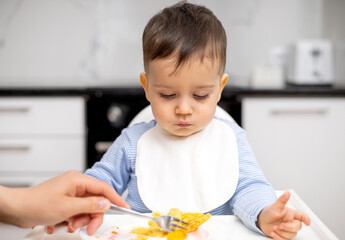adorable baby boy kid eating peach pancake,mother hand feeding child. wide open mouth hungry cute...