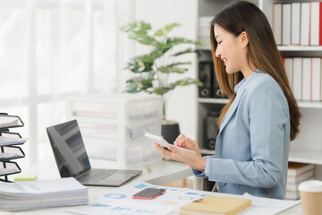 Asian businesswoman in formal suit in office happy and cheerful during using smartphone and working