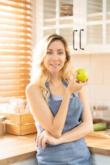 Happy Healthy fit woman with green apple at home kitchen. Diet or nutrition food with copy space. Beautiful female stand with happy face, enjoy eating apple, healthy foods for health care wellness.