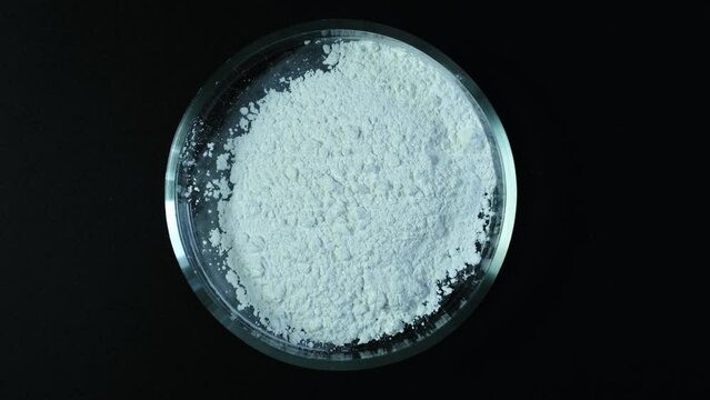 Silicon dioxide powder or Silicon (IV) oxide, in Petri dish, top view. Food additive E551, anti-caking agent. Video, Rotation motion. Counterclockwise rotation.