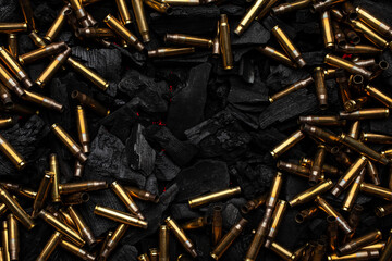 Empty shells from weapons on black smoldering coals. Consequences of the war. Dark back.