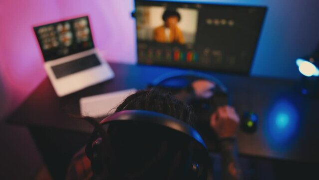 Young man in glasses working on video editing on computer doing montage and color correction. Professional man hand making edits on a special panel. Concept of creating video content.