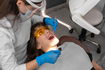 Dentist checks for violations in the natural bite after treatment with articulation paper. Adjustment of the seal after installation.