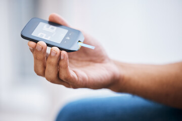 Hand, diabetes and measurement with a man in his home holding a blood glucose meter for disability awareness. Healthcare, medical and sugar with a diabetic male testing insulin levels in his house