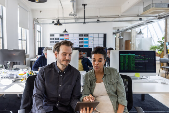 Coworkers working together on a presentation on a digital tablet - Powered by Adobe